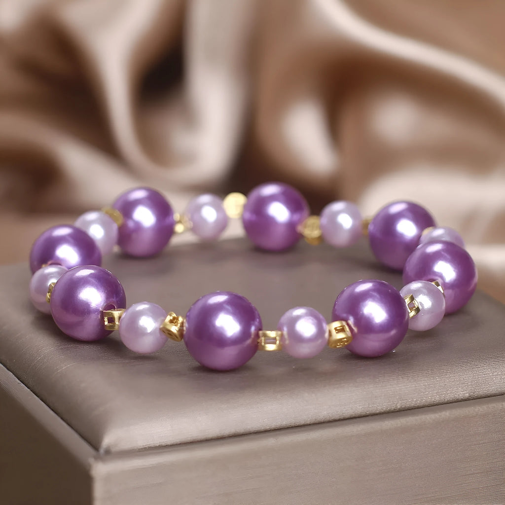 Purple shell pearl bracelet with letter coin accent on white background