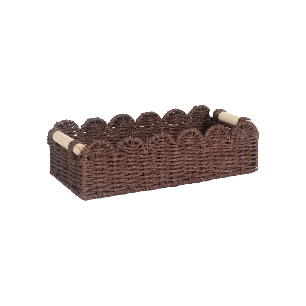 Modern woven rectangular storage basket in khaki colour on a wooden table holding remote controls and pens.