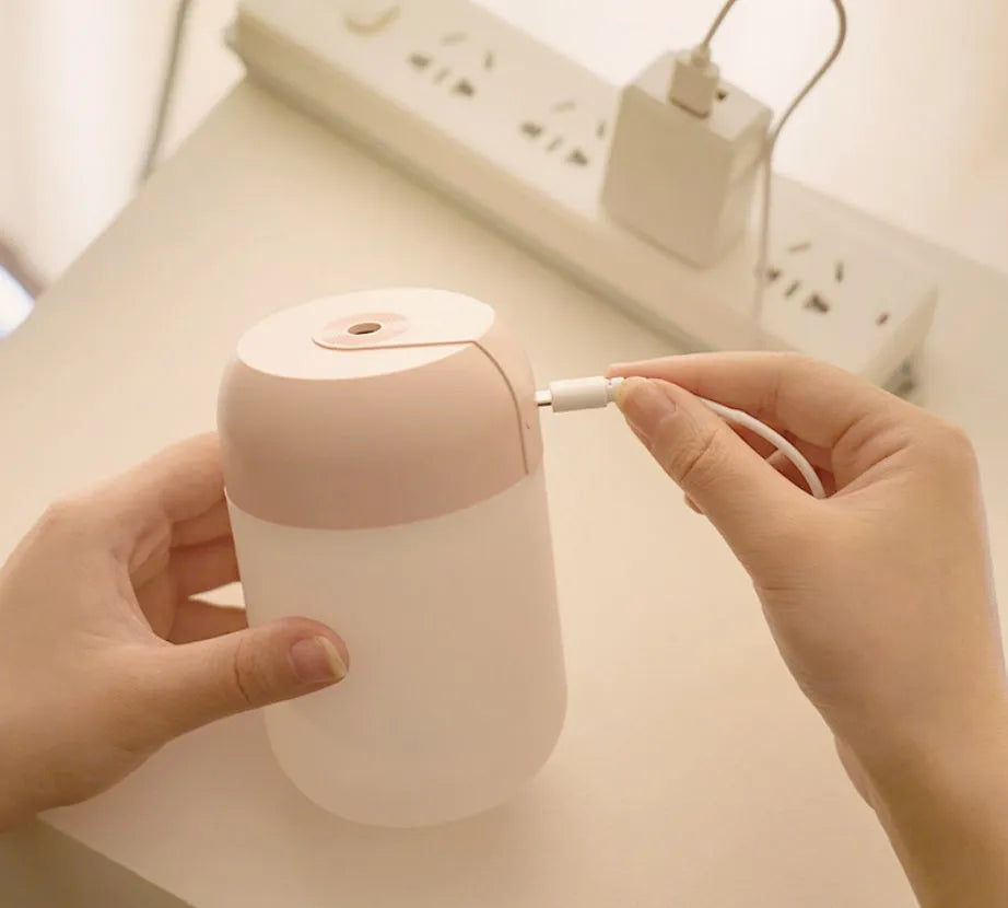 Small white cylindrical USB humidifier with aromatherapy function on a wooden desk.