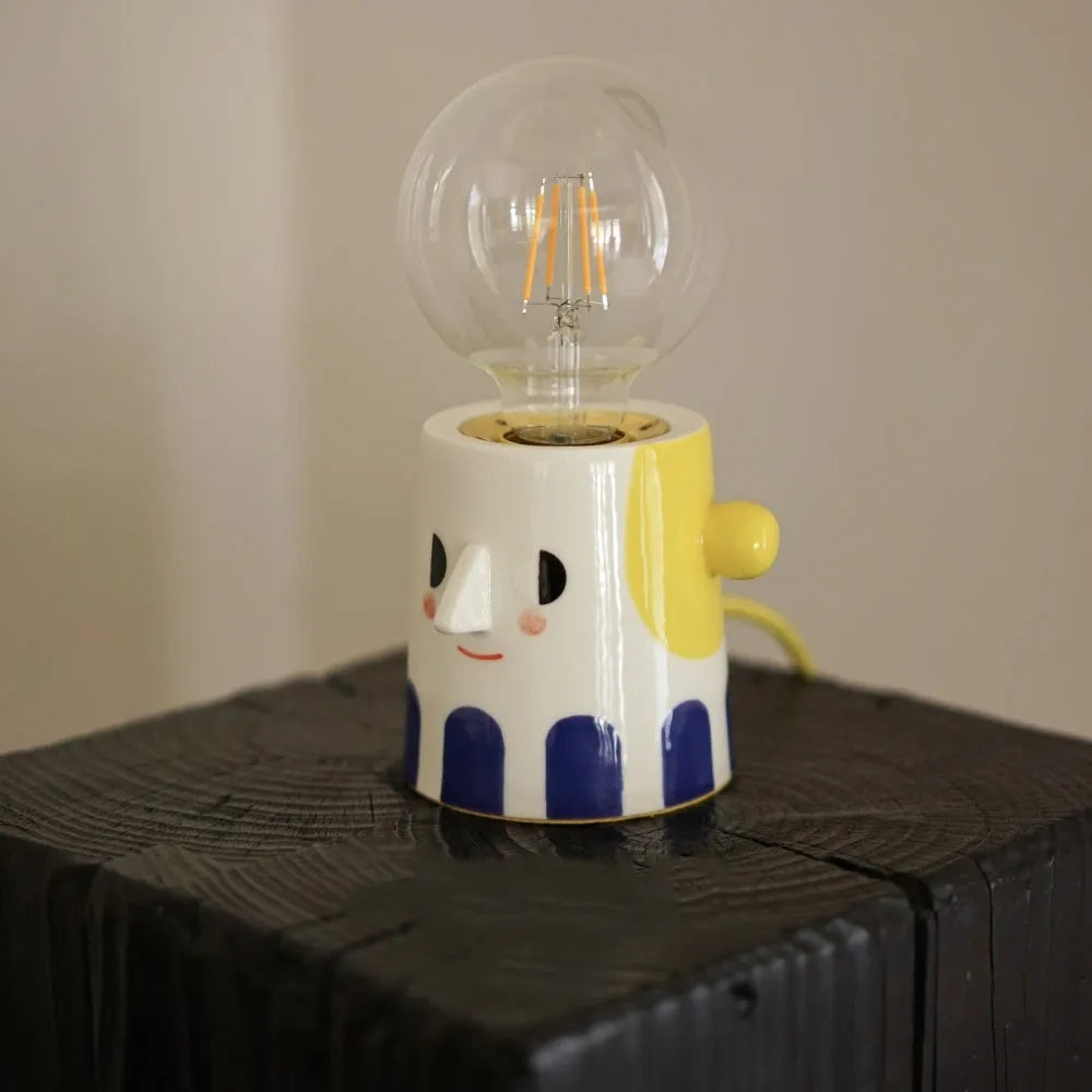 Handmade ceramic bedside lamp with ball headlight colour design on a table.