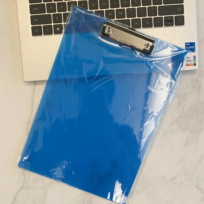 A4 transparent plate clipboard with metal clip, shown in blue colour on a desk with paper.