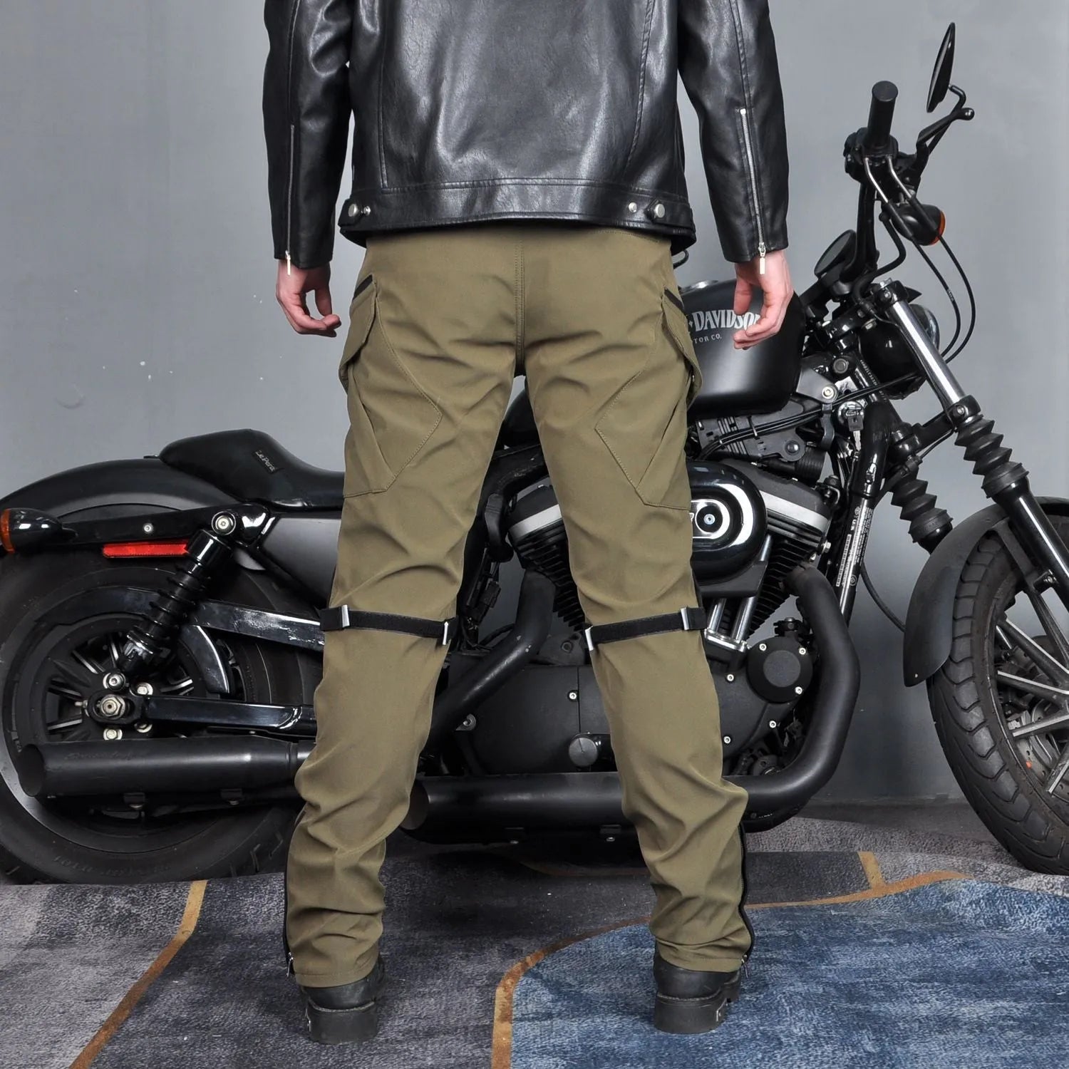 Men's green waterproof motorcycle trousers with belt and protective knee pads laid out flat.