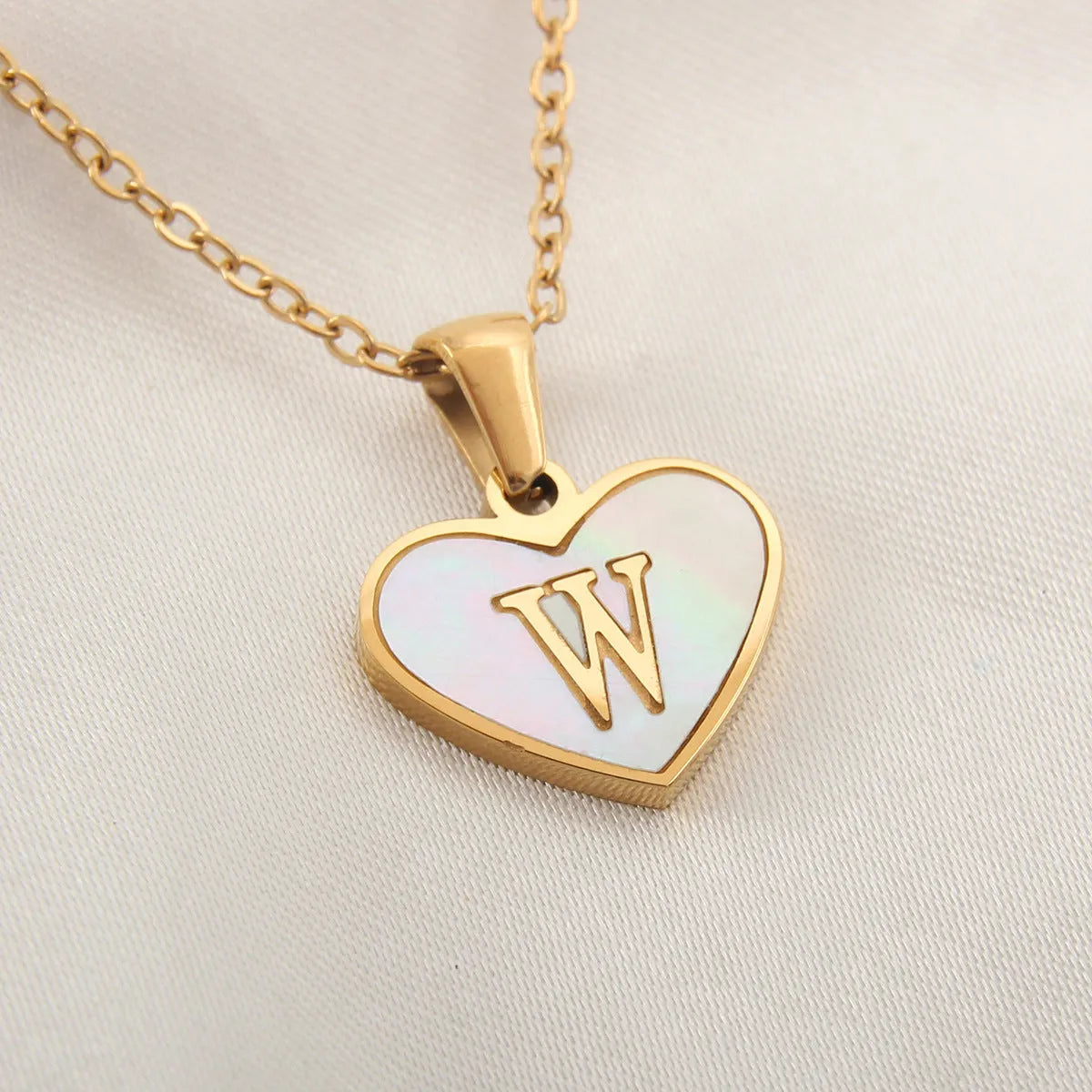 Gold plated heart-shaped necklace with a personalised initial letter and white shell detail on a 50cm adjustable chain.