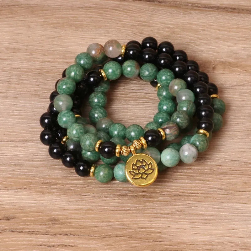 Green and black elastic beaded alloy bracelet on a wrist.
