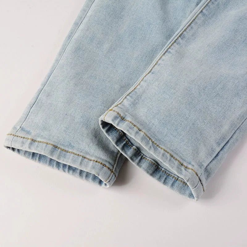 Light blue men's elastic slim fit jeans with hot diamond patch and whisker scrape detailing