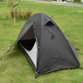 Black single person hiking tent with aluminium poles pitched outdoors, showing double-layer design.