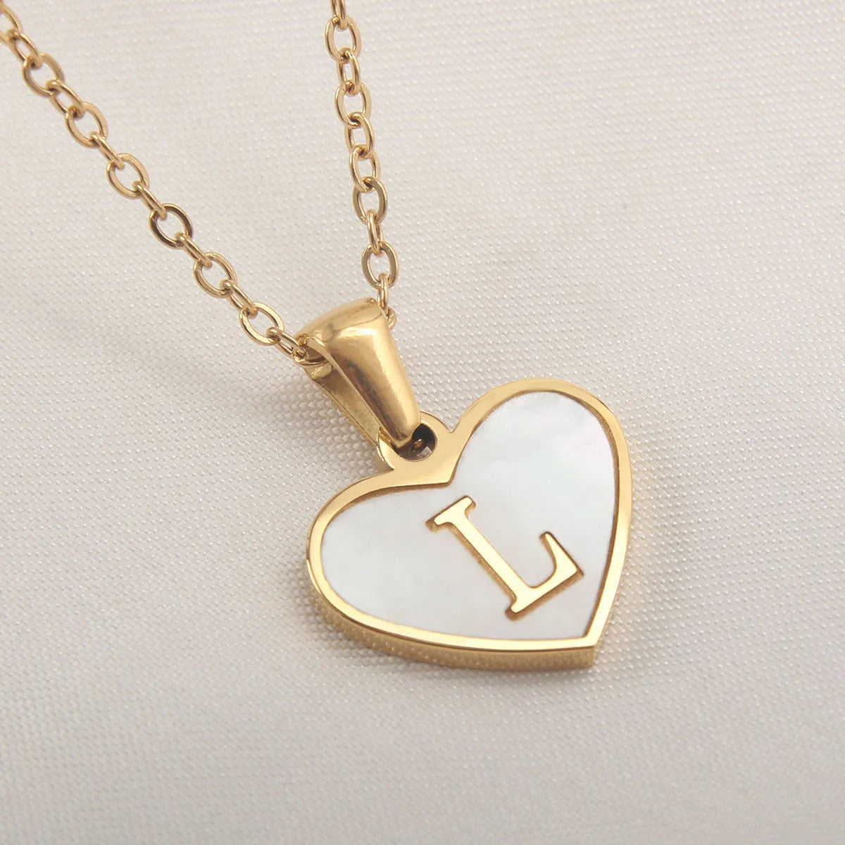 Gold plated heart-shaped necklace with a personalised initial letter and white shell detail on a 50cm adjustable chain.
