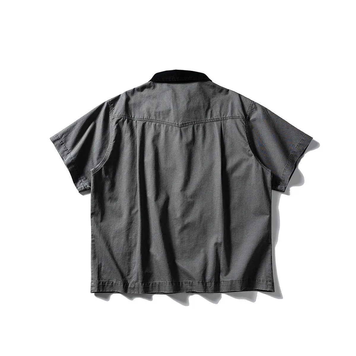 A man's khaki loose-fit short-sleeve cotton overalls shirt with button front and patch pockets.