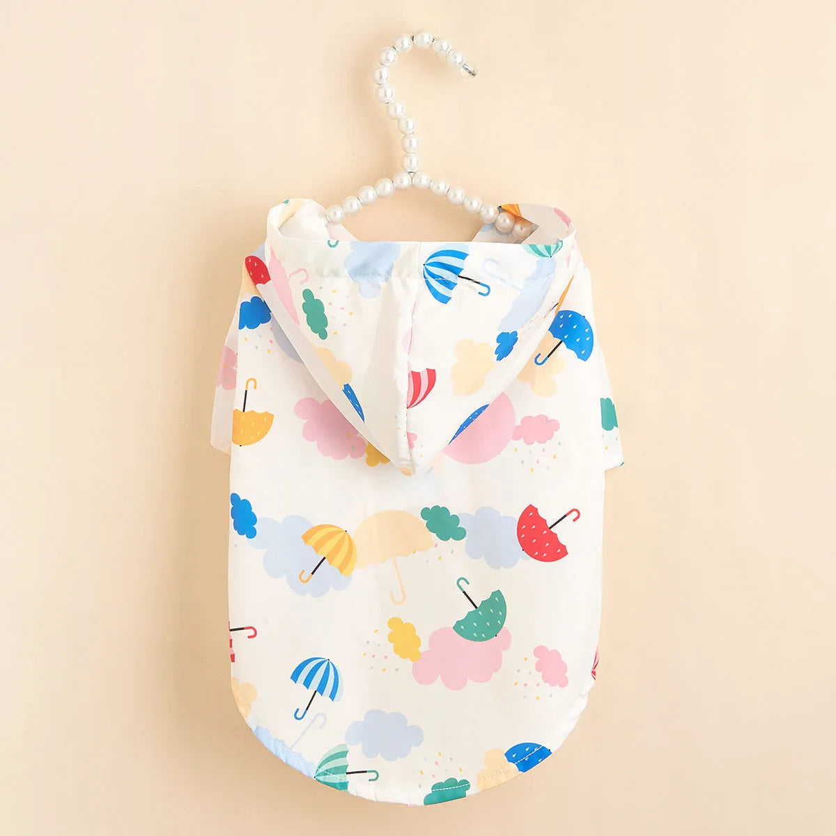Colourful cartoon umbrella pattern pet raincoat for a small dog on a grey background.