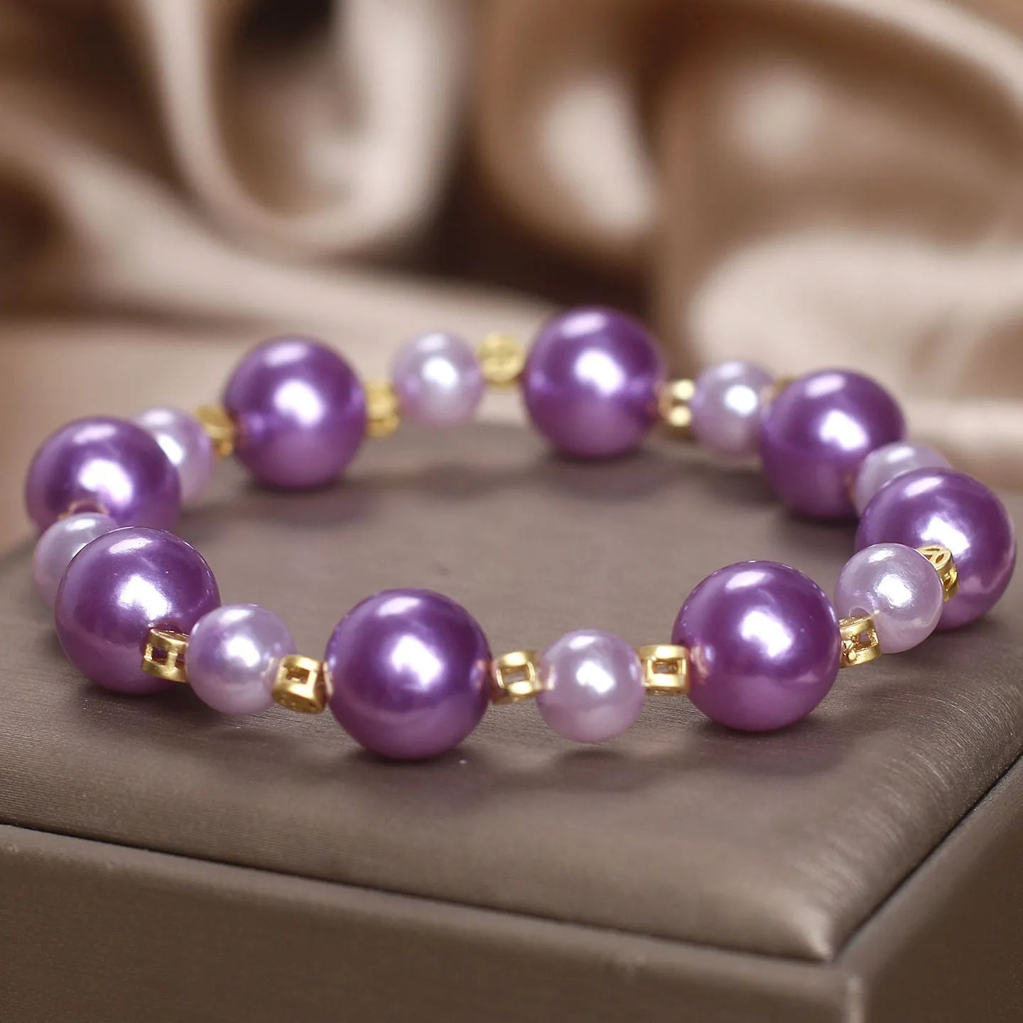 Purple shell pearl bracelet with letter coin accent on white background