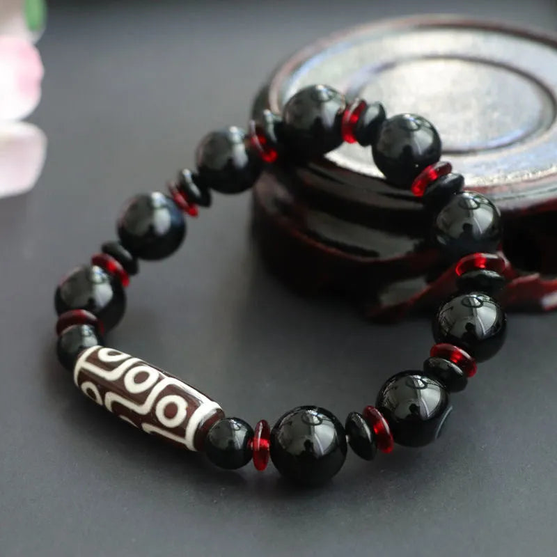Hand-woven black agate dzi bead bracelet with geometric design measuring 11mm diameter