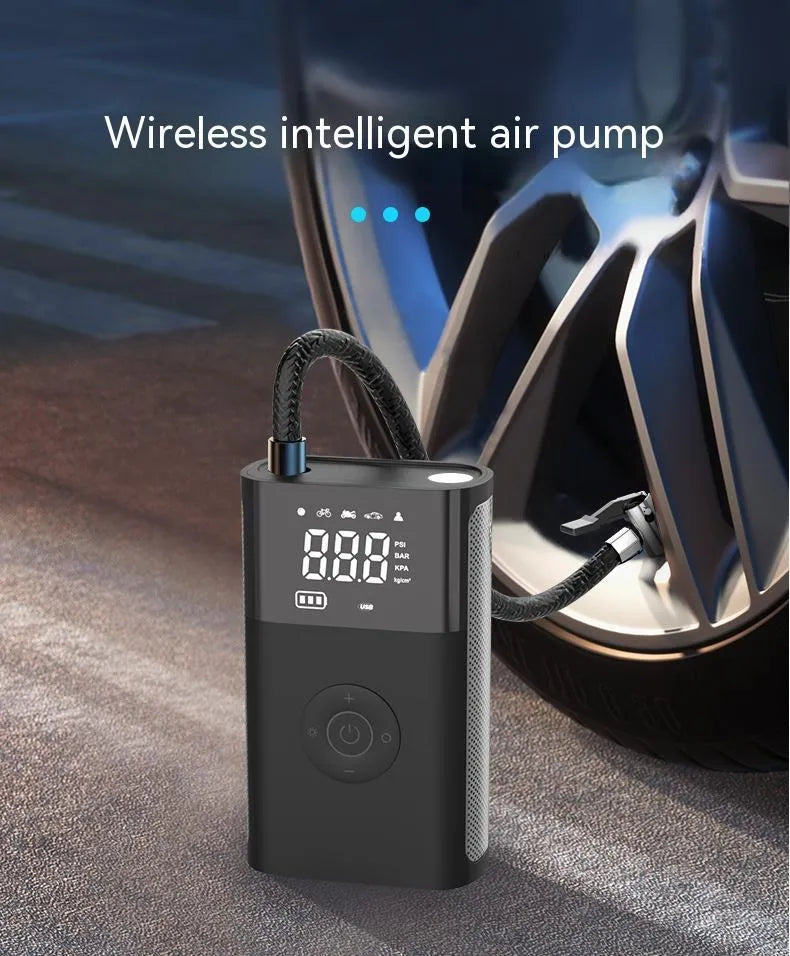 Handheld wireless digital tyre inflator with display screen, LED light, and multiple nozzle adaptors on a table.