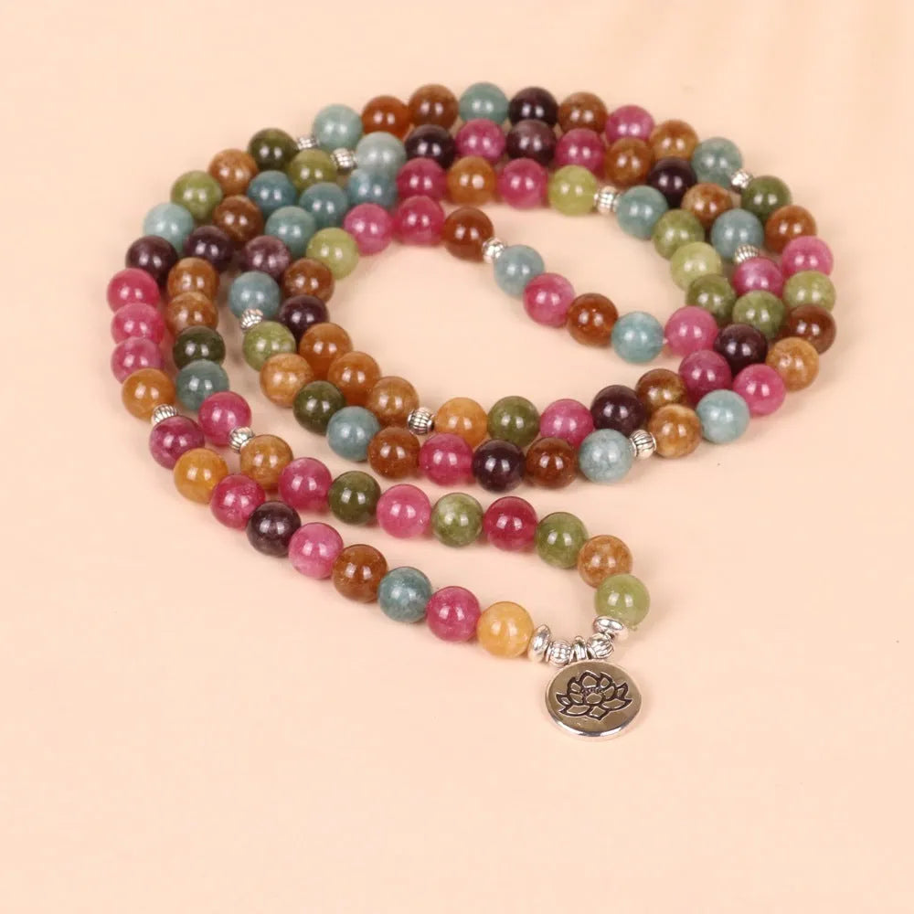 Close-up of a multi-layer beaded bracelet with 108 alloy beads and a central lotus pendant in a tourmaline colour.