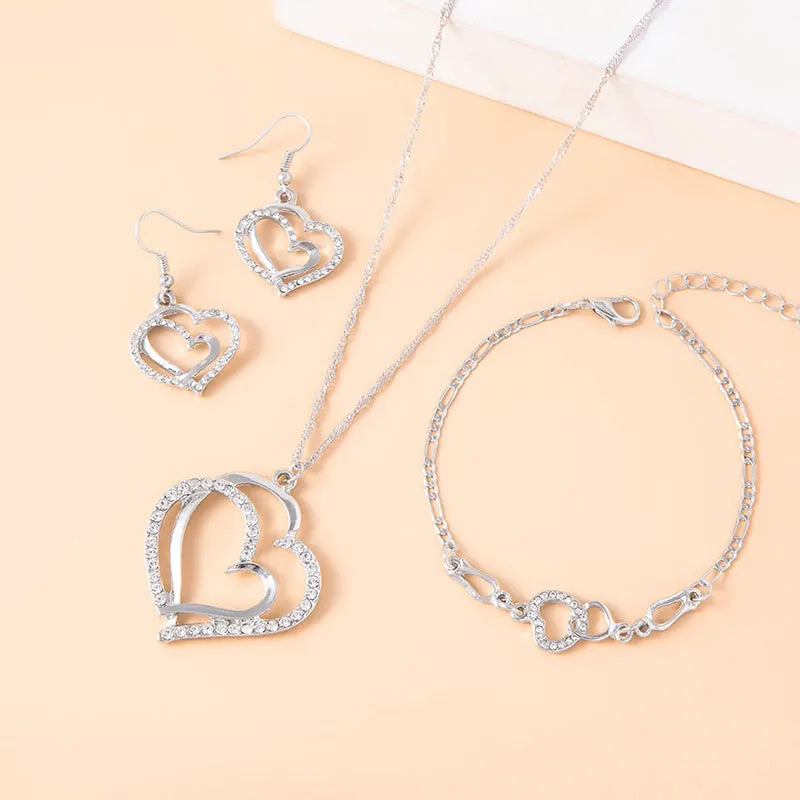 Silver romantic crystal heart jewelry set with bracelet necklace earrings on white background