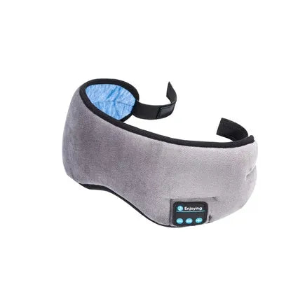Black Bluetooth sleep mask with built-in speakers lying flat on a surface with a charging cable.