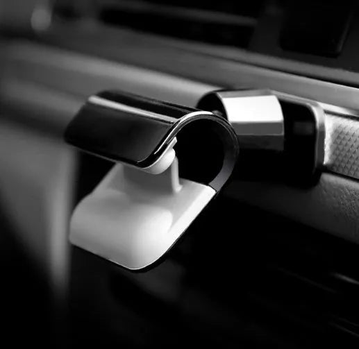 Black gravity car phone holder with 360-degree rotation mounted on a car dashboard.