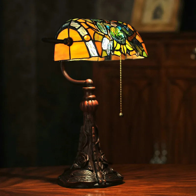 Tiffany table lamp with coloured glass lampshade and stained glass resin base on wooden desk