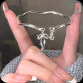 Close-up of an adjustable silver girlfriends bracelet with a bow-shaped bell opening clasp on a zinc alloy band.