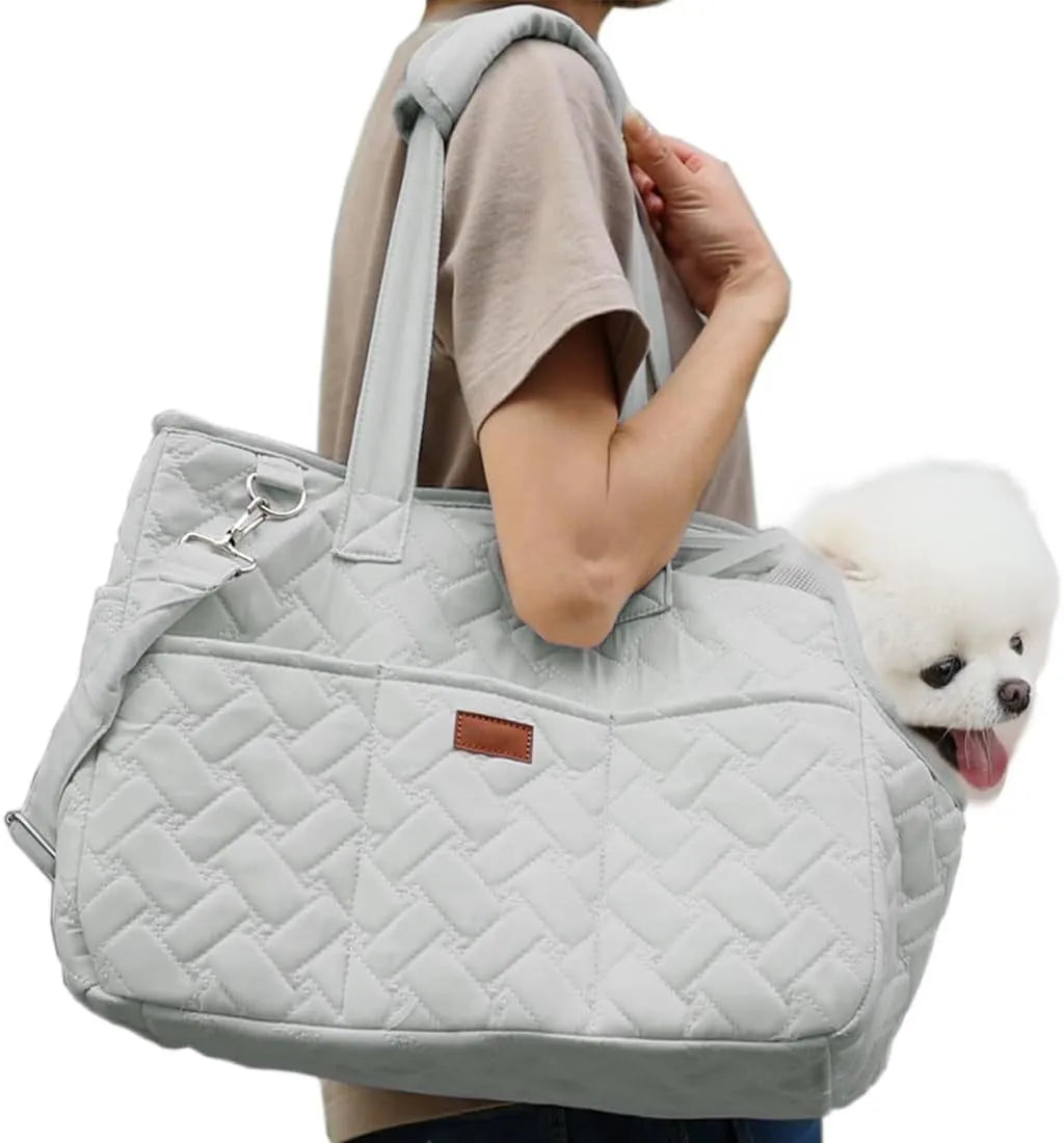 Grey pet carrier handbag with mesh panels and shoulder strap on a table