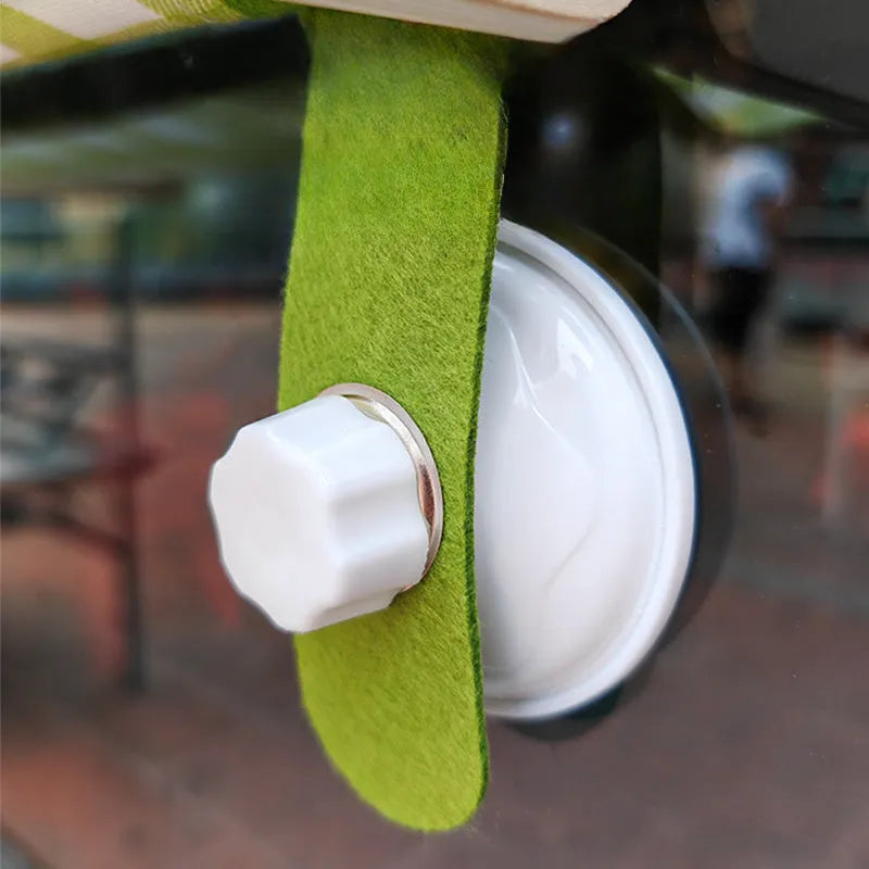 Pink wooden cat hammock with suction cups attached to a window, showing a removable cat paw print fabric seat.