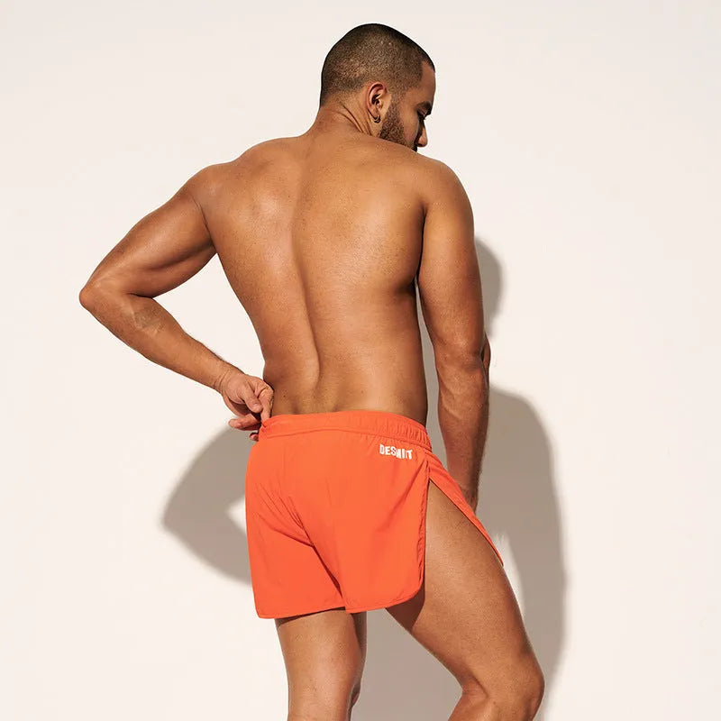 Men's loose-fit polyester surfing pants on a beach, shown in orange red, fluorescent green, and black colour options.