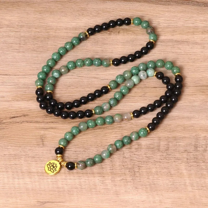 Green and black elastic beaded alloy bracelet on a wrist.