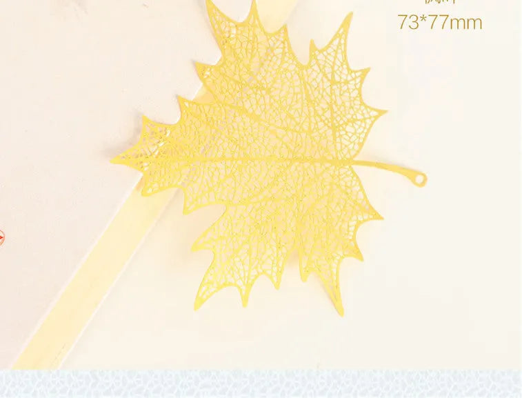 Brass metal bookmark with hollow leaf design and rose gold tassel in a presentation box.