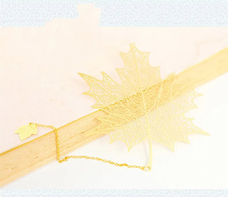 Brass metal bookmark with hollow leaf design and rose gold tassel in a presentation box.