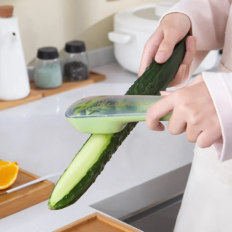 Dark green vegetable peeler with a storage tube and stainless steel blade on a kitchen counter.