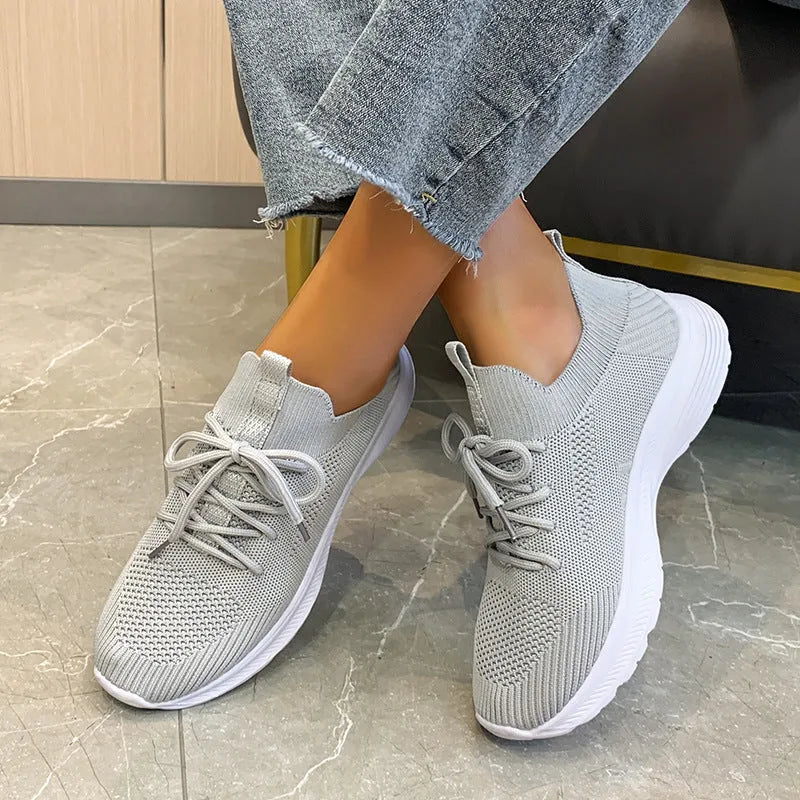 Women's low-top mesh running shoes in creamy white with Flyknit upper and rubber sole.