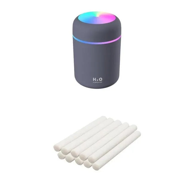 Pink USB-powered mini humidifier with colourful lights on a wooden desk
