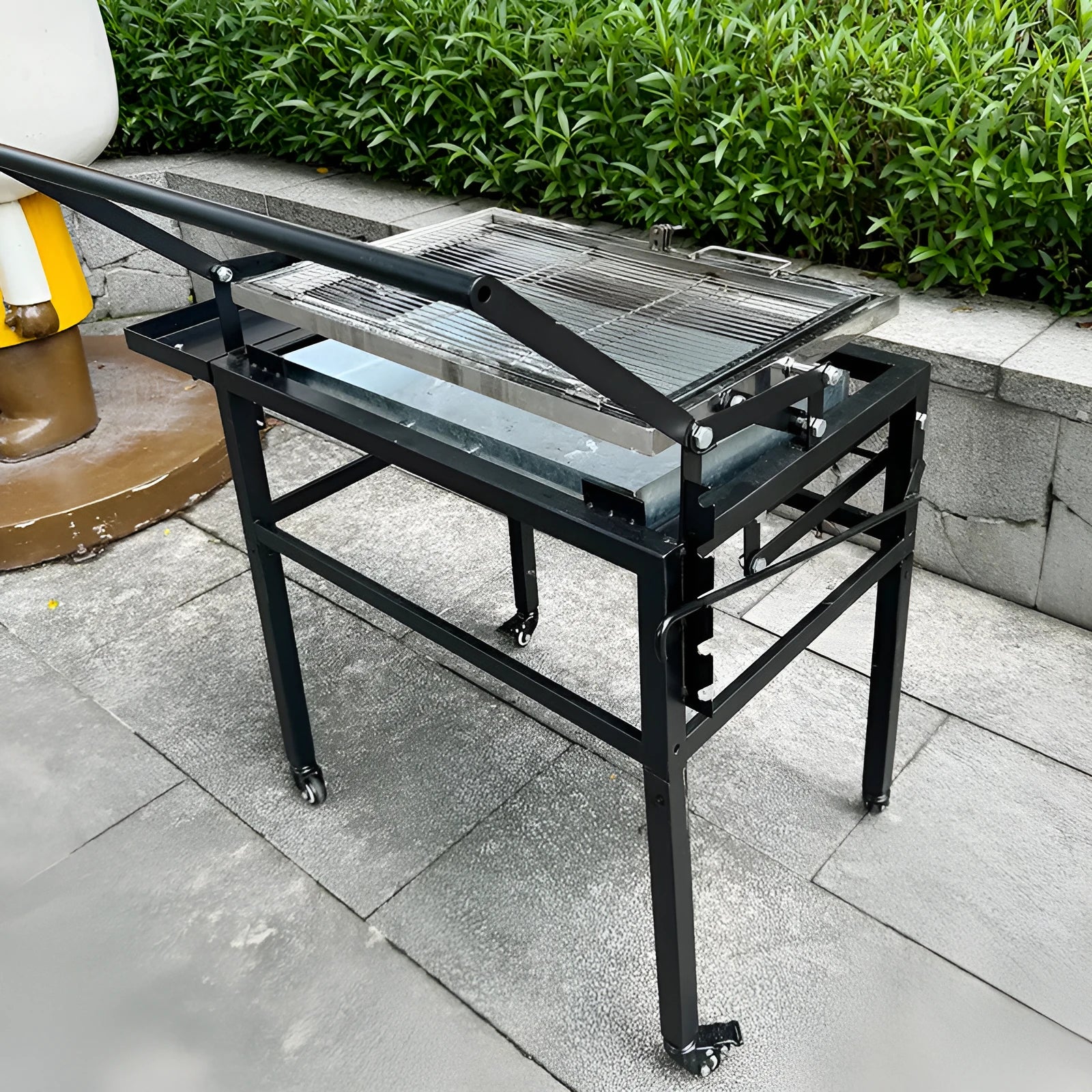 Large foldable Flip BBQ charcoal grill with detachable legs set up in a garden.