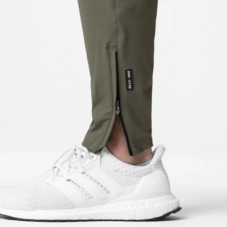 Man wearing dark grey loose-fit ankle-tied polyester running trousers for fitness.