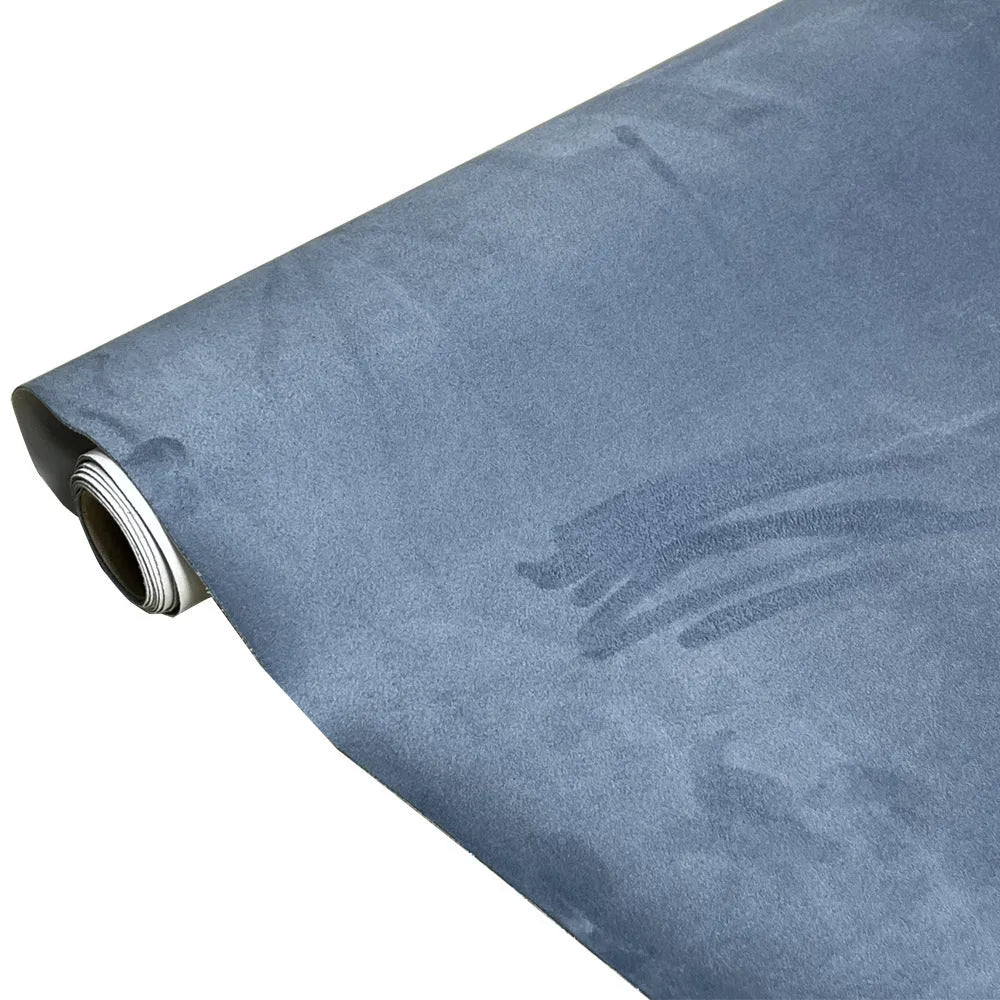 Roll of self-adhesive black leather suede fabric with adhesive backing visible, showing texture and a cut sheet sample.