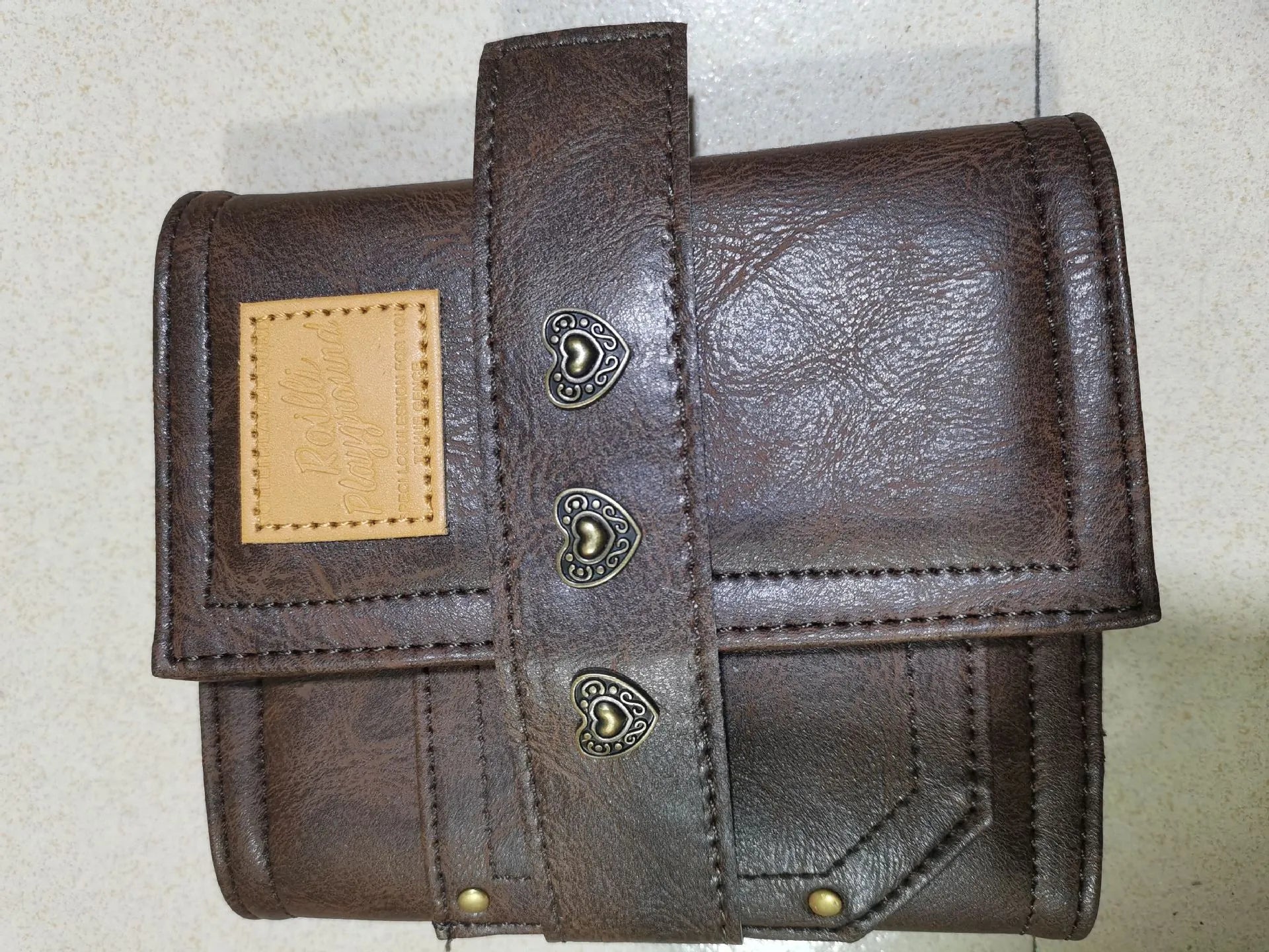 Brown A7 size notebook with a retro leather-look PU cover and metal buckle closure, lying open on a desk.