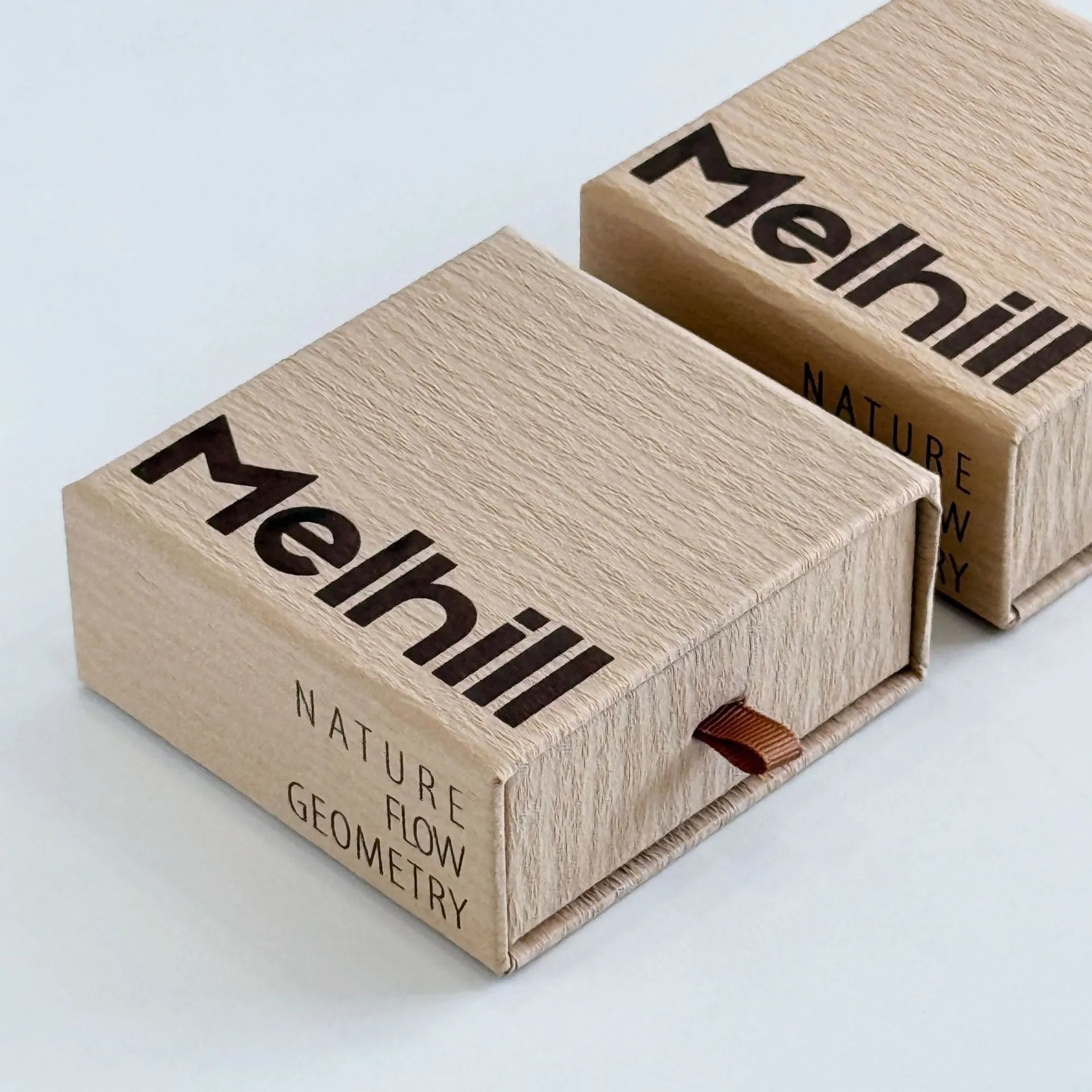 Beige brown cardboard drawer jewellery box with a storage bag beside it