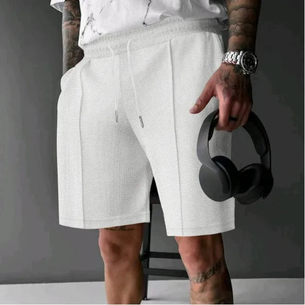 Solid colour polyester five-point sports shorts in Khaki, side view, showing elastic waist and above-knee length