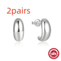 Close-up of a glossy C-shaped sterling silver stud earring with a post back, shown on a neutral background.