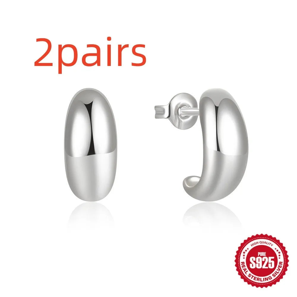 Close-up of a glossy C-shaped sterling silver stud earring with a post back, shown on a neutral background.