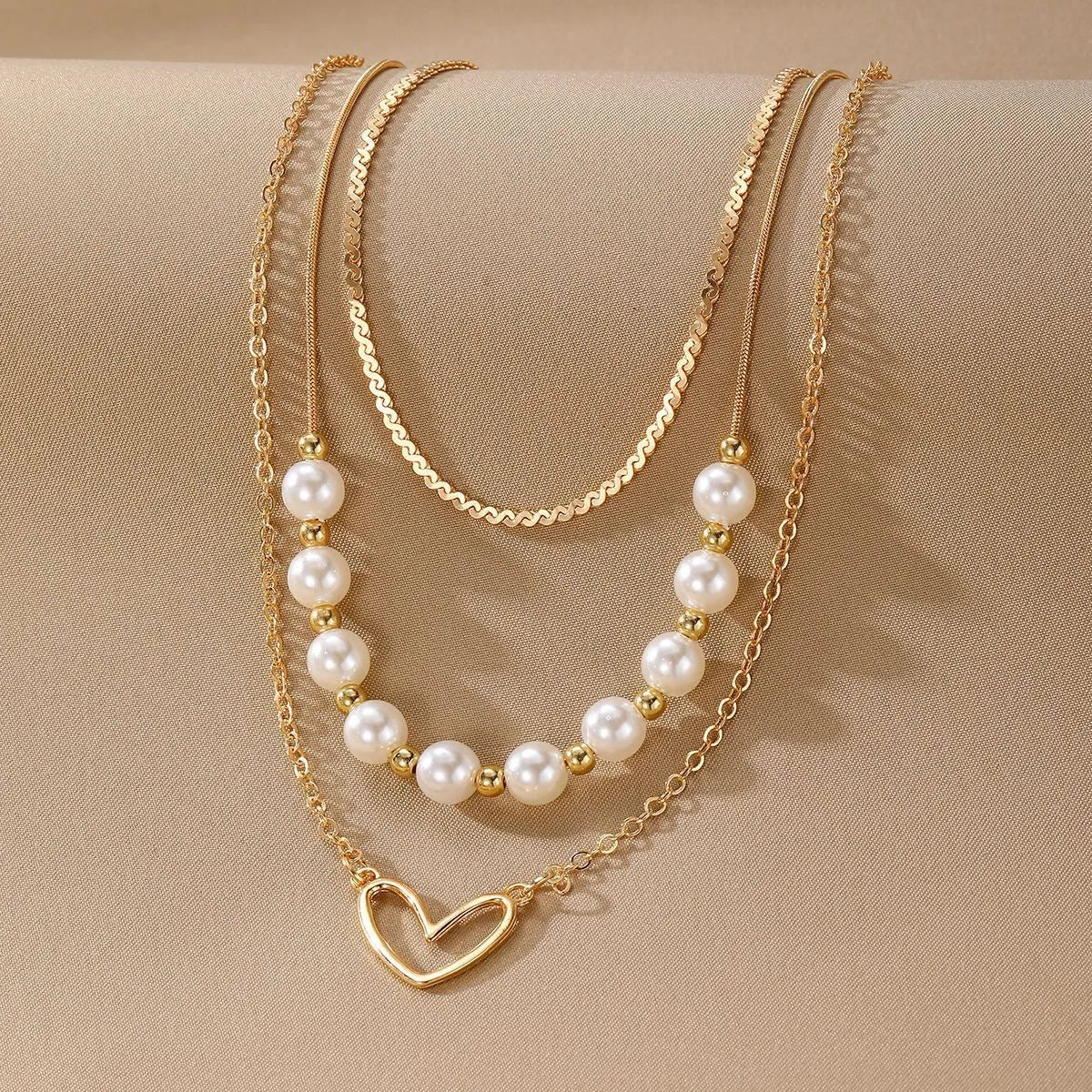 Vintage gold necklace with heart pendant on adjustable pearl chain, showing electroplated finish and love motifs