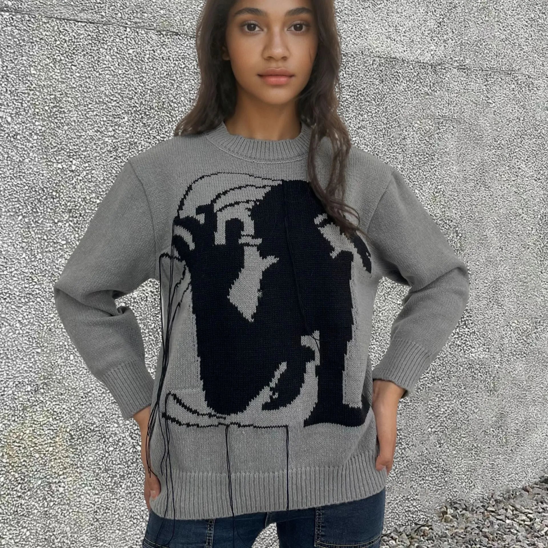 Grey women's loose alpaca wool sweater with abstract pattern and tassel design details on sleeve.