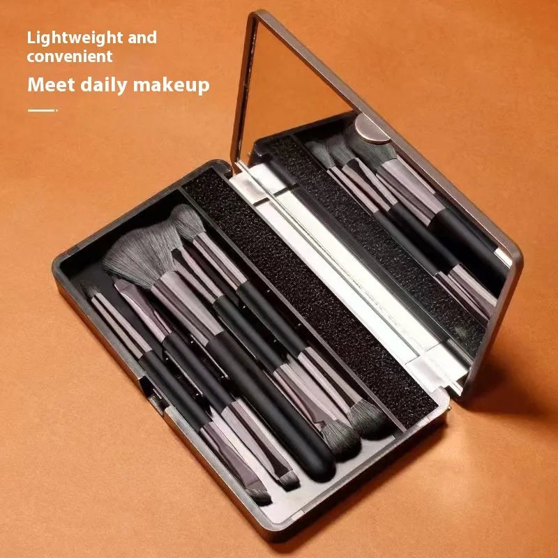 Portable makeup brush set with mirror showing gold or silver handled eyeshadow brushes.