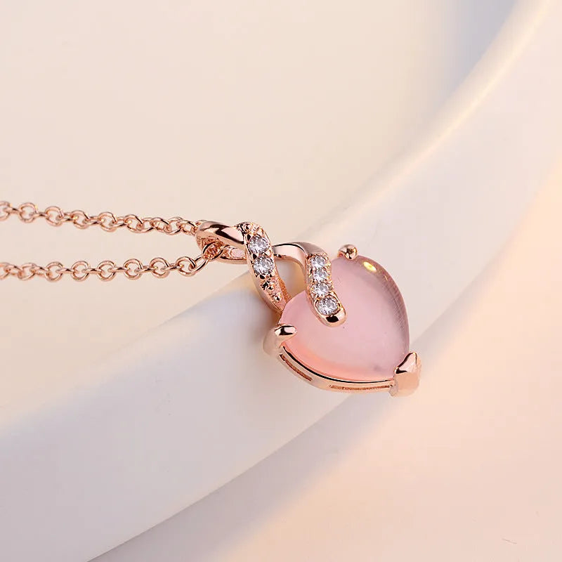Rose gold necklace with heart-shaped pink crystal pendant and cross chain design
