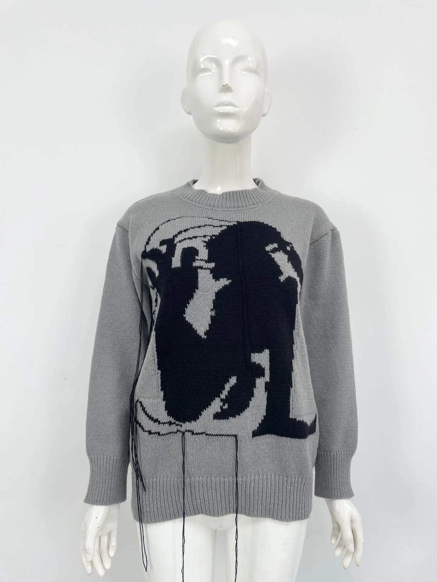 Grey women's loose alpaca wool sweater with abstract pattern and tassel design details on sleeve.