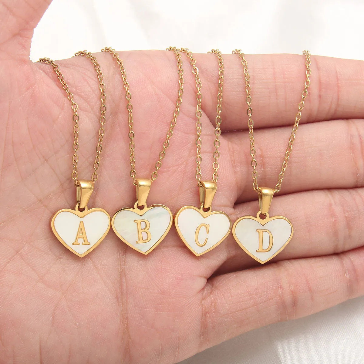 Gold plated heart-shaped necklace with a personalised initial letter and white shell detail on a 50cm adjustable chain.