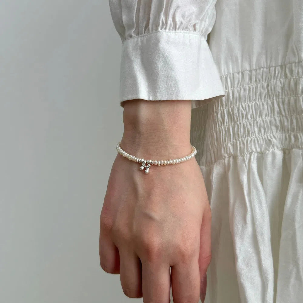 Women's natural freshwater pearl bracelet in 925 silver with letter shape charm on neutral background