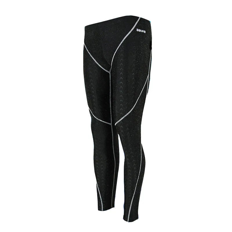 Men's nylon cropped swimming trunks in a black and green colour block design, laid flat.