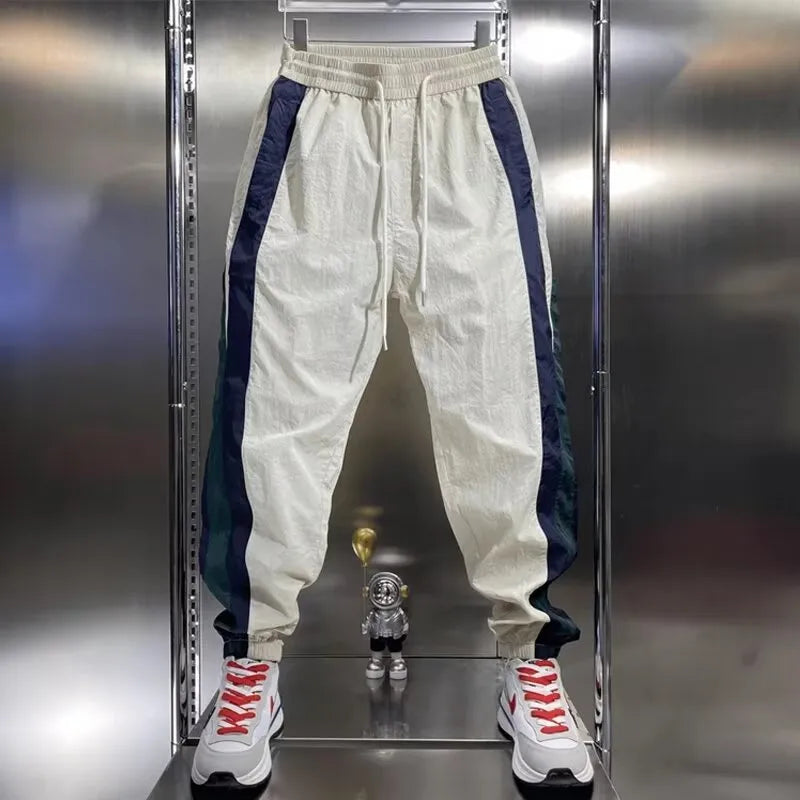 Men's loose fit contrast stripe jogger sports pants in black, showing drawstring waist and tapered leg