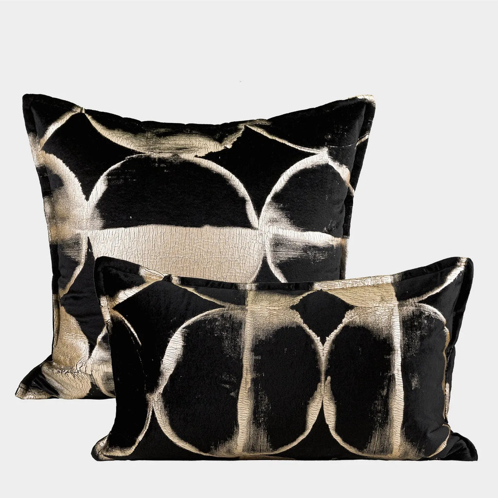 Black and gold abstract pattern decorative cushion cover on a grey sofa.