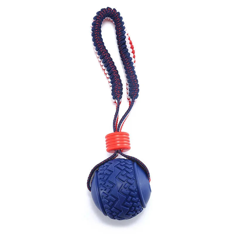 Blue dog toy with a textured rubber ball attached to a cotton rope, shown on grass.